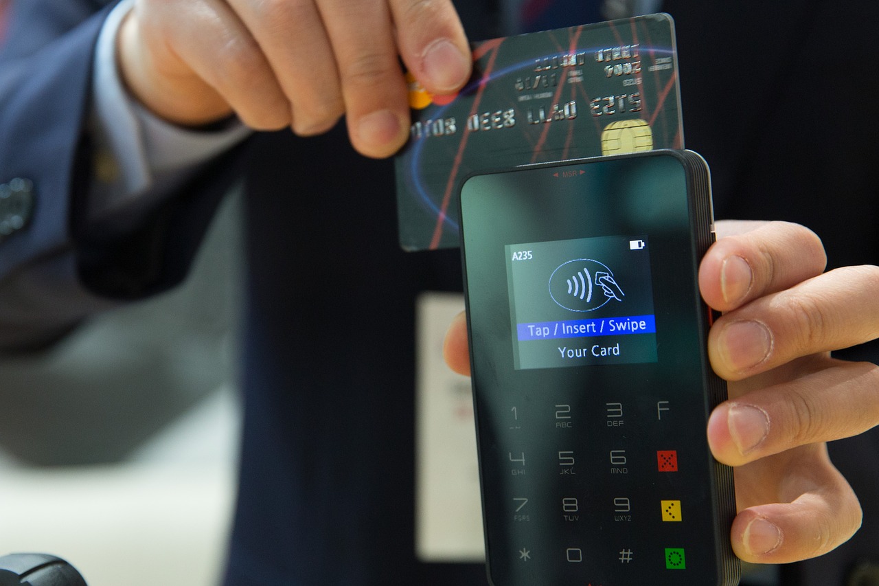 Small business payment options you should consider - a man swipes his credit card through an EFT terminal.